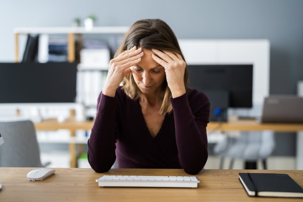 Woman holding head at her desk