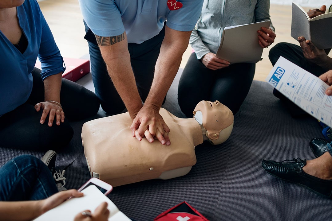 Person demonstrating CPR on a dummy in First Aid CPR AED training class