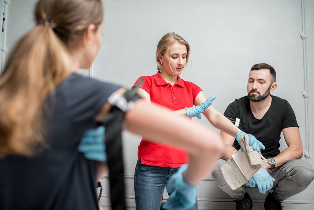 A group of people learning to apply the tourniquet to prevent bleeding during a training indoors